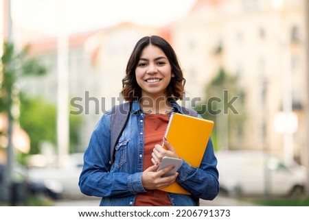 Beautiful Young Arab Female Student Standing Outdoors With Workbooks In Hands, Happy Attractive Middle Eastern Woman Posing Outside On City Street, Carrying Backpack And Smiling At Camera, Copy Space Royalty-Free Stock Photo #2206791373