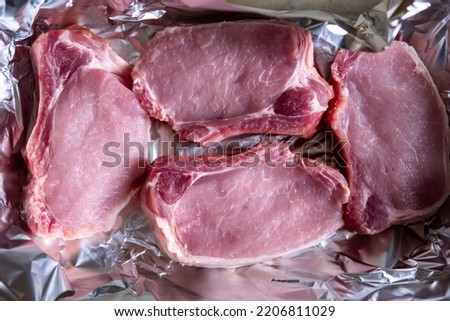 Raw meat steaks on foil. Pig meat. Preparation for cooking in the oven.