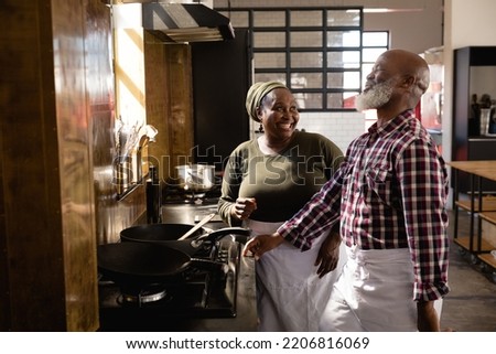 Side view of an Senior African man and an African woman at a cookery class, discussing while cooking, laughing at each other Royalty-Free Stock Photo #2206816069