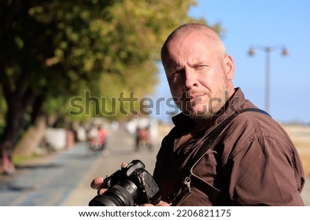 adult man makes a photo on a camera with a large lens. In the street on a sunny day in summer