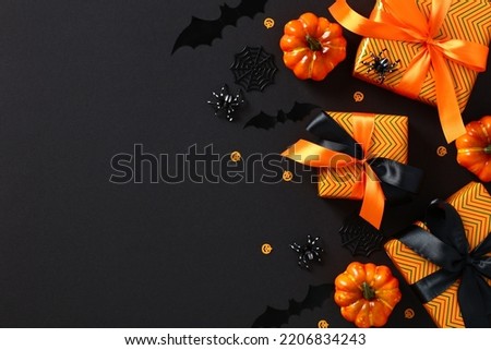 Halloween holiday composition. Gift boxes, orange pumpkins, spiders, bats, confetti on dark black background. Happy Halloween banner design.
