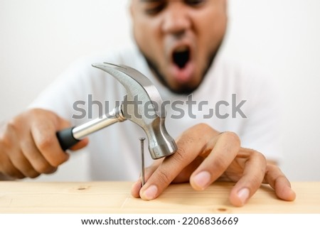 The carpenter was injured by hammer and nails. He misused the hammer and stuck it in his hand. Accidents during work require accident insurance. Royalty-Free Stock Photo #2206836669