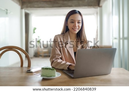 Young happy pretty asian woman using laptop at cafe.