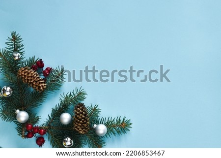 Christmas composition. Fir tree branches, red berries, cones and silver balls on a blue background. Christmas, winter, new year concept. Flat lay, top view, copy space. banner