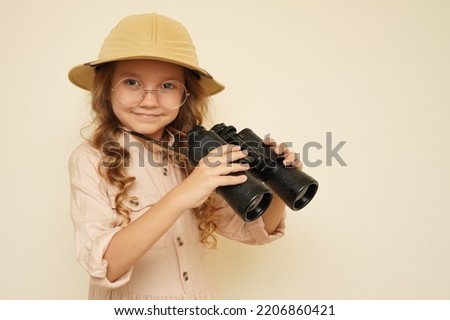 Child discoverer.  Unique child.  Traveler child.  Young travel blogger.  Little cute girl in a fashionable suit and hat for trips to Safari with binoculars in her hands.  Trendsetter. Royalty-Free Stock Photo #2206860421