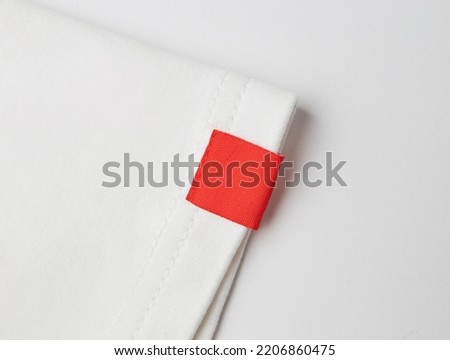 blank red color clothing label on white t shirt sleeve Royalty-Free Stock Photo #2206860475