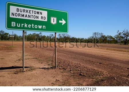 green road sign to Burketown QLD Australia dirt road and bushes in the background