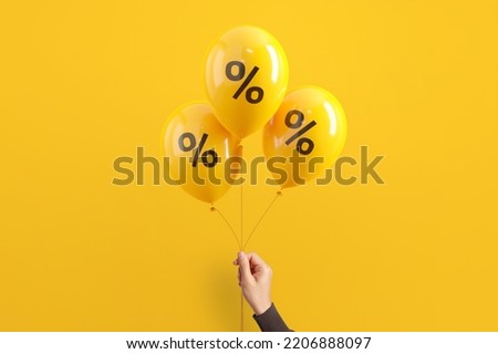 Hand of woman holding balloons with percent on yellow background, Minimal, Sale and discount. Royalty-Free Stock Photo #2206888097