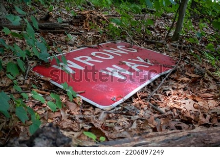 wrong way red and white street sign  broken and on the forest ground