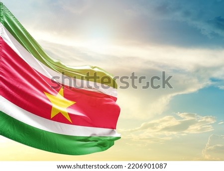 Suriname national flag waving in beautiful sky.