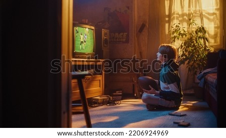 Young Sports Fan Watches American Football Match on Retro TV in His Room with Dated Interior. Boy Supporting His Favorite Team, Feeling Proud When Players Score a Goal. Nostalgic Childhood. Royalty-Free Stock Photo #2206924969