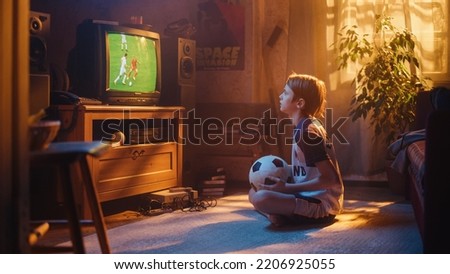 Young Excited Sports Fan Watches a Soccer Match on TV at Home. Curious Boy Supporting His Favorite Football Team, Feeling Proud When Players Score a Goal. Nostalgic and Retro Childhood Concept. Royalty-Free Stock Photo #2206925055