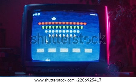 Close Up Footage of a Retro TV Set Screen with an 8 Bit 2D Eighties Inspired Console Arcade Video Game. Nostalgic Shooter Game, Player Battle with Swarm of Aliens and Wins. Royalty-Free Stock Photo #2206925417
