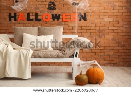 Interior of living room decorated for Halloween with couch and pumpkins