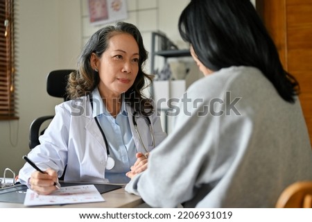 Professional senior Asian female doctor meets with her patient to explain and summarize the surgery plan and treatment in the office. Royalty-Free Stock Photo #2206931019