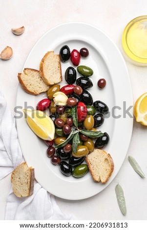 Plate with different kinds of tasty olives and bread on light background, closeup