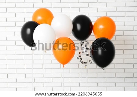 Halloween balloons near white brick wall