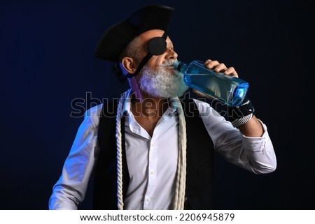 Old pirate drinking rum on dark background