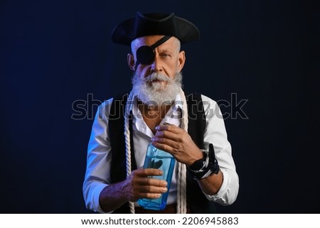 Old pirate with bottle of rum on dark background