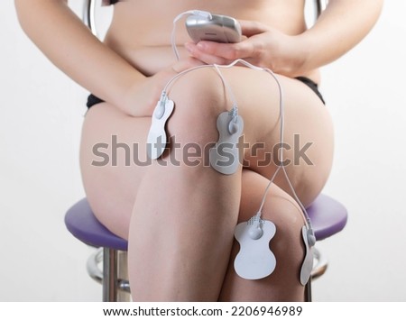 Electrodes of modern acupuncture and anti-cellulite massagers on the legs of a girl in problem areas. Home physiotherapy Royalty-Free Stock Photo #2206946989
