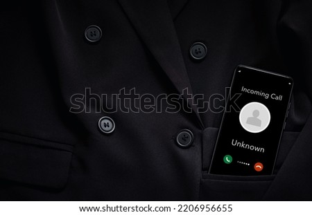 closeup smart phone screen with incoming call by unknown from black suit pocket, technology and connecting concept