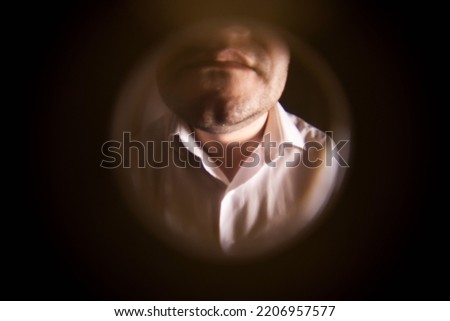 View from the peephole. A man in a white shirt is standing near the front door. The concept of breaking the law. Debt collection, collector. Close-up Royalty-Free Stock Photo #2206957577