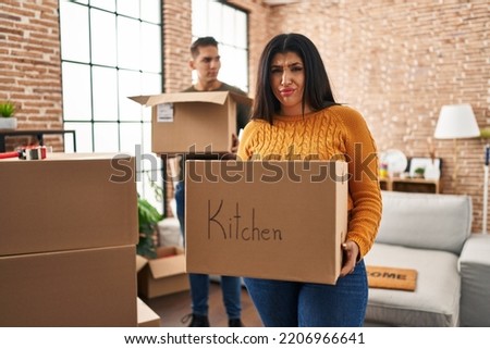 Young couple moving to a new home with cardboard boxes skeptic and nervous, frowning upset because of problem. negative person. 