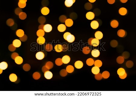 abstract holiday background: yellow bokeh lights in darkness
