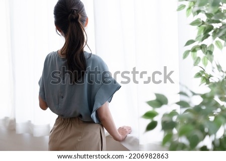 woman standing by the window Royalty-Free Stock Photo #2206982863