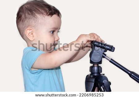 adorable cute little baby toddler boy isolated with tripod for cameras.becoming a photographer.tools accessories for camera mirrorless or dslr,shop market online orders delivery.