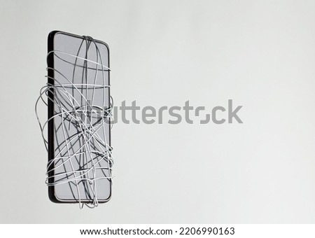smartphone coiled metal wire in the hands of a man, gray-green background, censorship of social networks. cancel cultural ban, erase Royalty-Free Stock Photo #2206990163