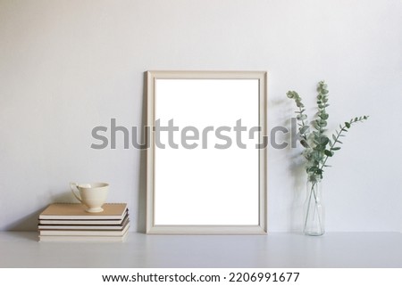 A white wooden frame and green leaves, books and coffee cup with natural light. 