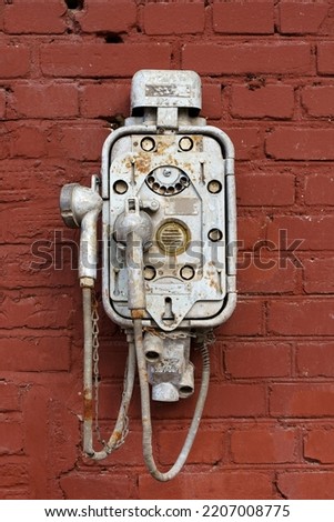 Old vintage telephone on a street brick wall. Steampunk technology, design, retro style concept.