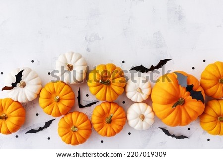 Halloween holiday border with party decorations of pumpkins and bats on white table top view. Happy halloween greeting card in flat lay style.