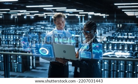 Technical Engineer and Project Administrator Using Computer in Modern Data Center Server Room Facility. Augmented Reality Productivity and Business Data Icons Appear From Worker's Laptop. Royalty-Free Stock Photo #2207031443