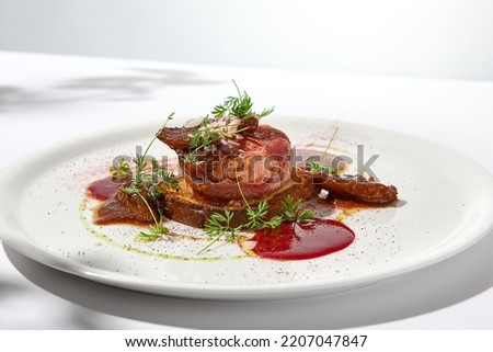 Baked camembert in parma ham on brioche with berry jam. Elegant food - hot appetizer of camembert and ham in summer menu. Cheese appetizer in fine dining. Summer menu Royalty-Free Stock Photo #2207047847