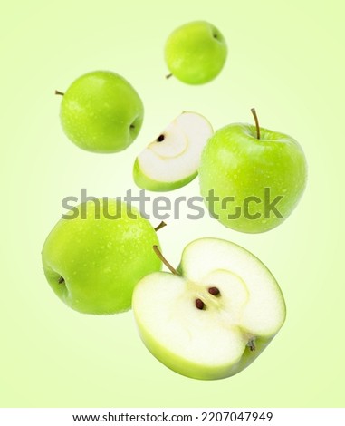 Fresh green apple fruit with water droplets levitate isolated on green background.