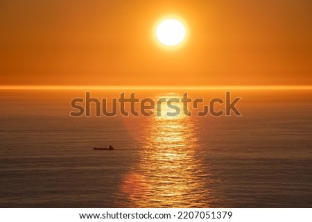 Wonderful landscapes in Norway. Nord-Norge. Beautiful scenery of a midnight sun sunset at Nordkapp (Cape North). Boat and globe on a cliff. Rippled sea and clear orange sky. Selective focus Royalty-Free Stock Photo #2207051379