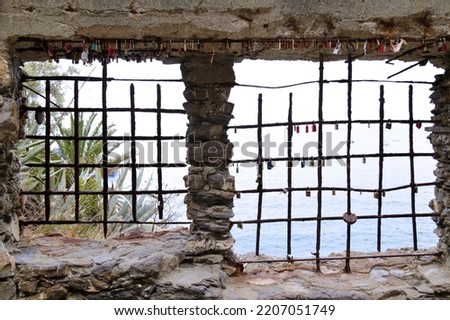 Barred window overlooking the sea with same love locks