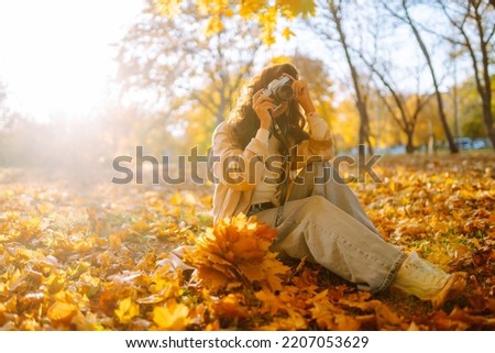 Beautiful woman taking pictures in the autumn forest.  Rest, relaxation, tourism, lifestyle concept.