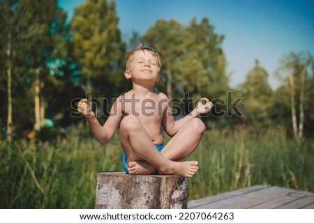 little boy doing yoga sitting on stub. summer nature on background. High quality photo