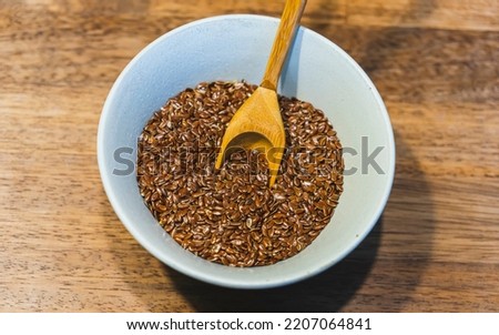 Selective focus on linseed or flax seed and a spoon in a white bowl on wooden background. Top view., close up and filtered photo. Healthy food concept. Copy for text. Noise effect and grainy texture.