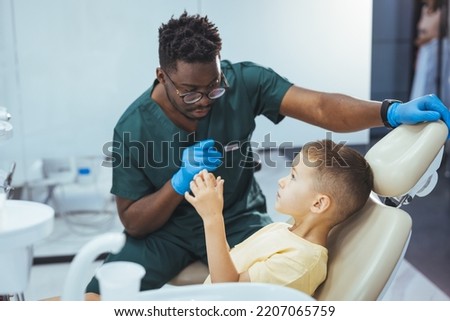 Dentists with a patient during a dental intervention to boy. Dentist Concept. Little boy at the dentist. Young dentist is treating cute little boy's teeth. Little boy at regular dental check-up