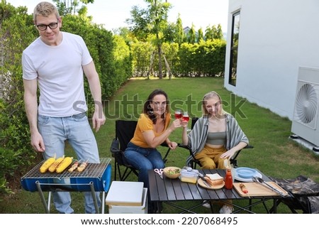 Group of happy family or friends with different ages making barbecue and celebrate outdoors with glass of red wine, grilling corn and enjoying BBQ party in backyard garden at home in summer day