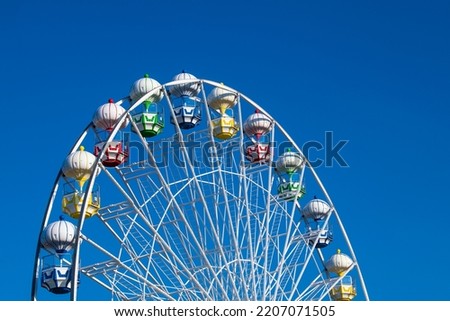 Closeup of A Colorful Ferris Wheel Over Blue Sky.