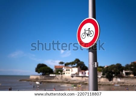 Warning sign with bicycle on beach with sea shore view. Bike restriction notice on ocean coast