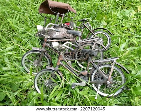 two miniature bicycles and one miniature rickshaw that are antique, unique, old and retro, souvenirs from Jogja for decoration are being placed on the green grass, metal toys, brown.