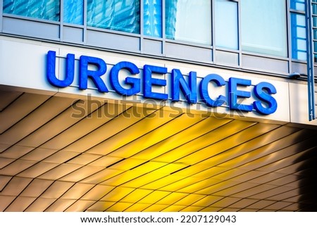 Low angle view of a french hospital emergency entrance sign ("urgences" in french) in blue capital letters.