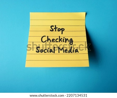 On blue background, handwritten stick note STOP CHECKING SOCIAL MEDIA, decision making to limit or stay away from social media to overcome addiction, gain more time, less distracted and less stressed Royalty-Free Stock Photo #2207134531