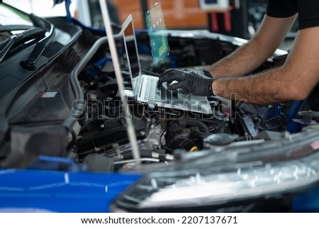 Mechanic Asian Arab man close up using laptop computer and diagnostic software to tuning fixing repairing car engine automobile vehicle parts using tools equipment in workshop garage support services Royalty-Free Stock Photo #2207137671
